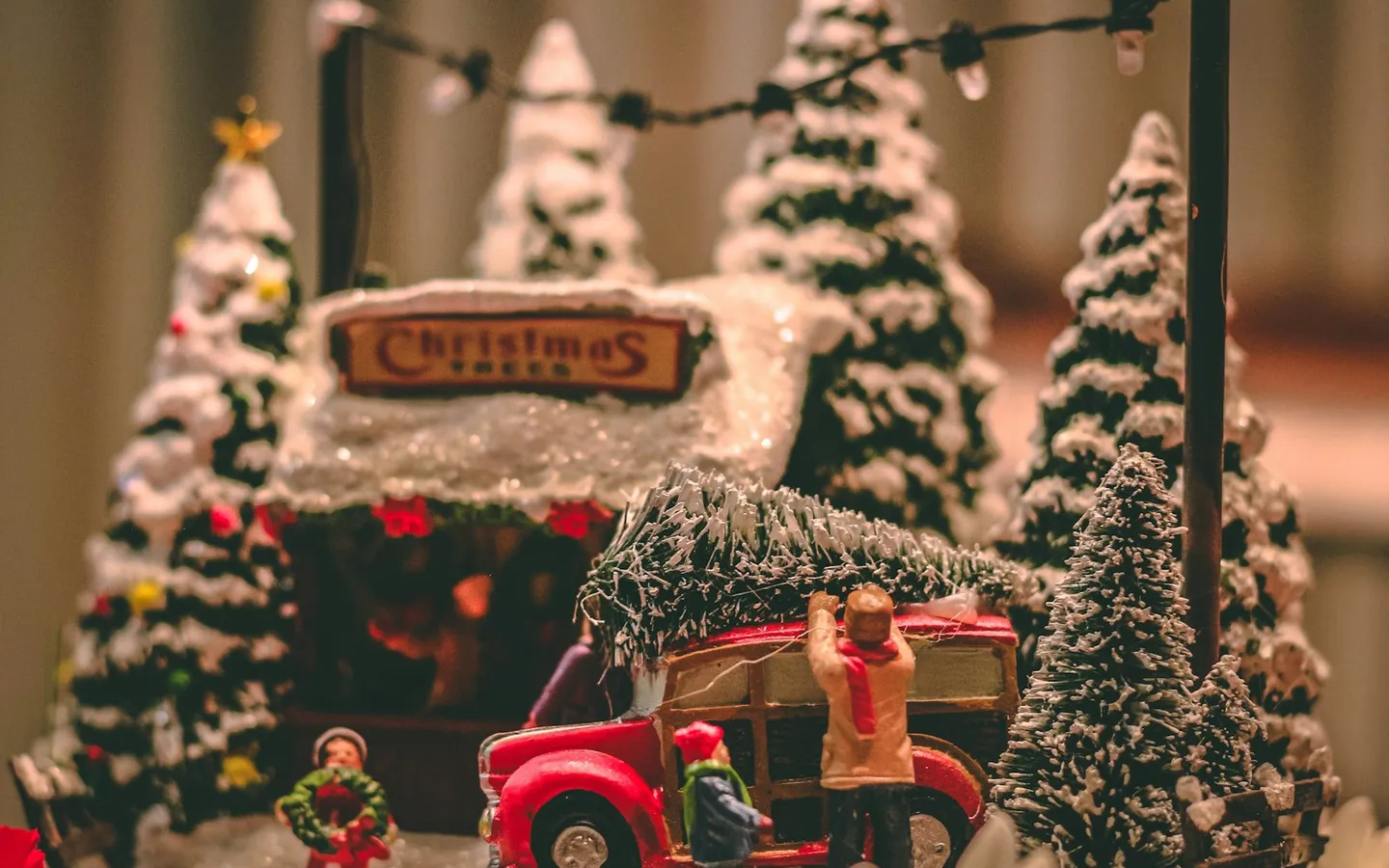 Miniature Christmas village with snowy bottle-brush trees and a red toy truck carrying a tree