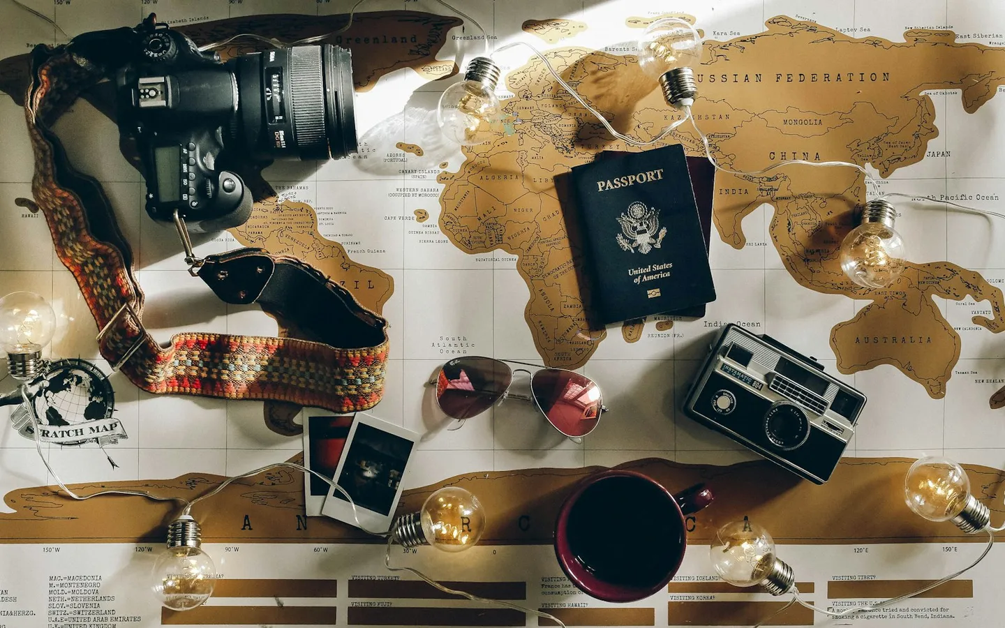 Passport, cameras and a coffee laid out on a world map
